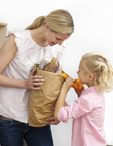 Little girl unpacking grocery bag with her mother